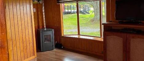 A wooden interior with a sofa, a television, and a large window.