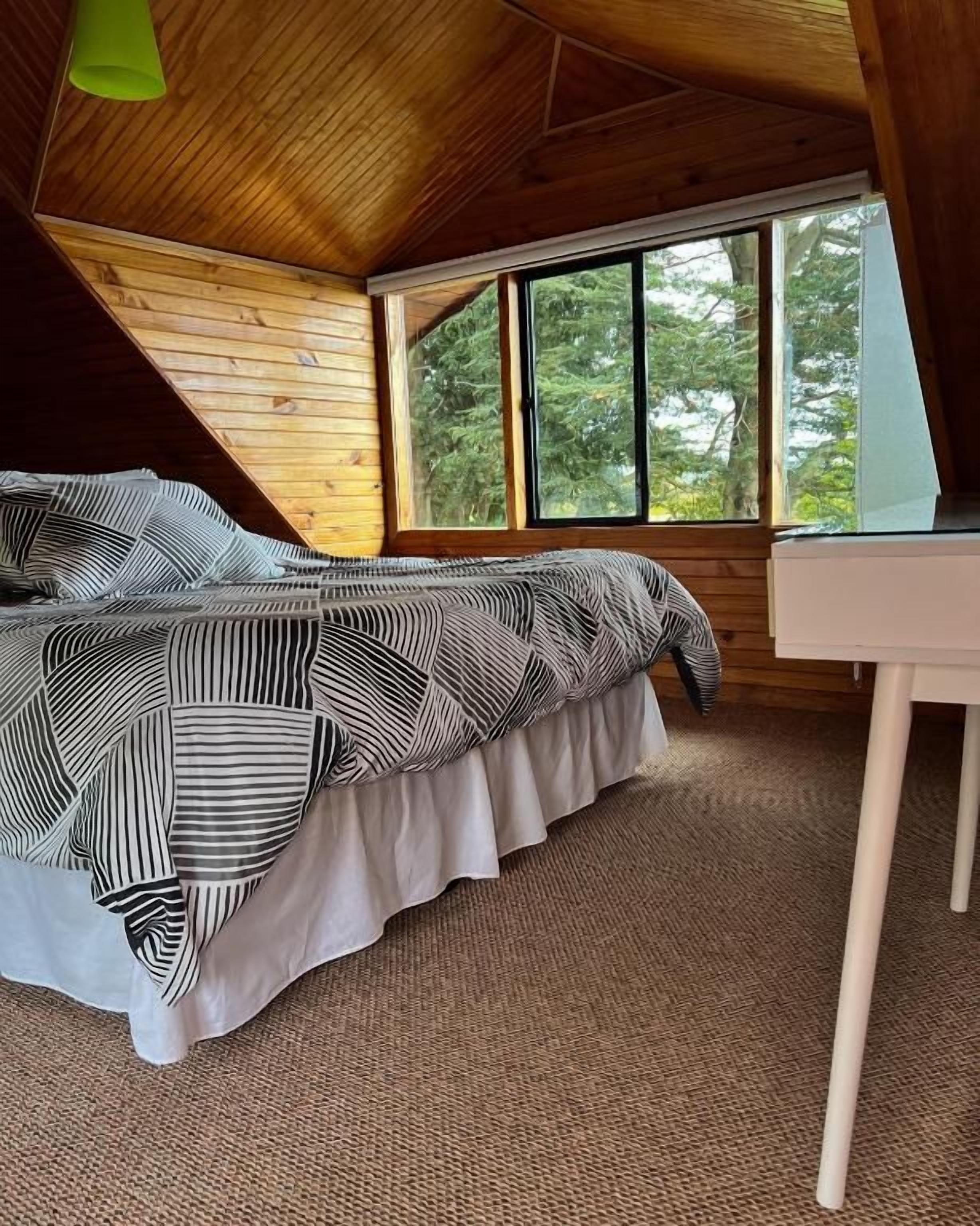 Un dormitorio con cama, escritorio y ventana.