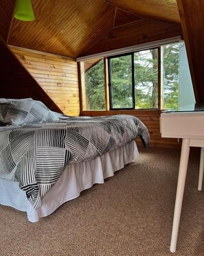 Un dormitorio con cama, escritorio y ventana.