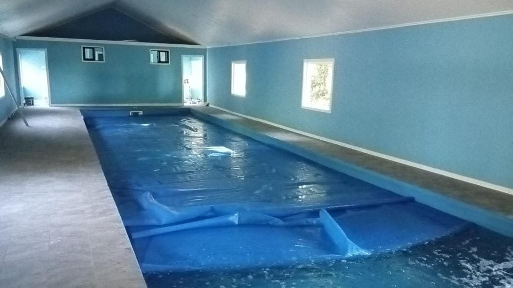 En inomhuspool med ett sluttande tak och väggar som är målade i en ljusblå färg.