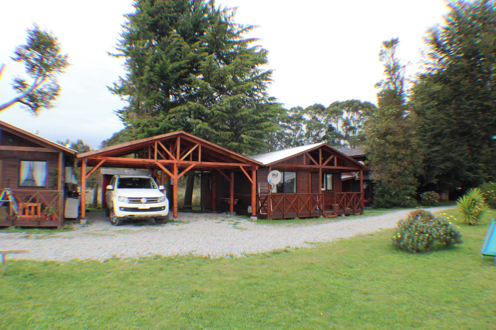 A two-story wooden building with a covered carport and a gravel driveway.
