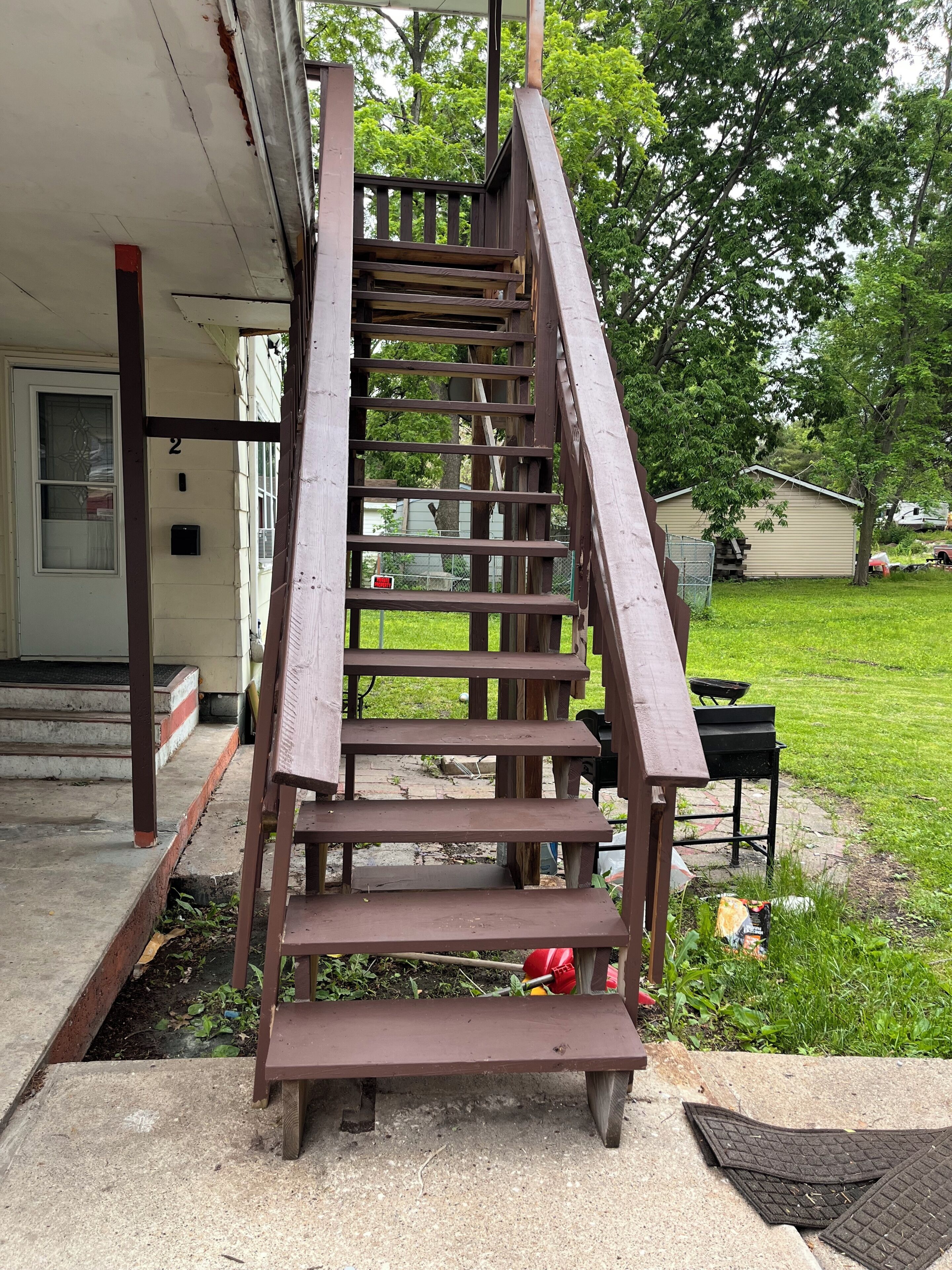 A wooden outdoor staircase leading to a house entrance.