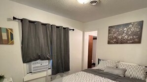 Un dormitorio con cama, cortinas, un cuadro y un radiador.