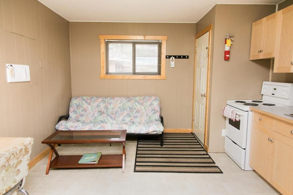A compact kitchenette with a stove, a small table, and a sofa.