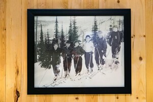 A framed photograph of a group of people skiing in a forest.