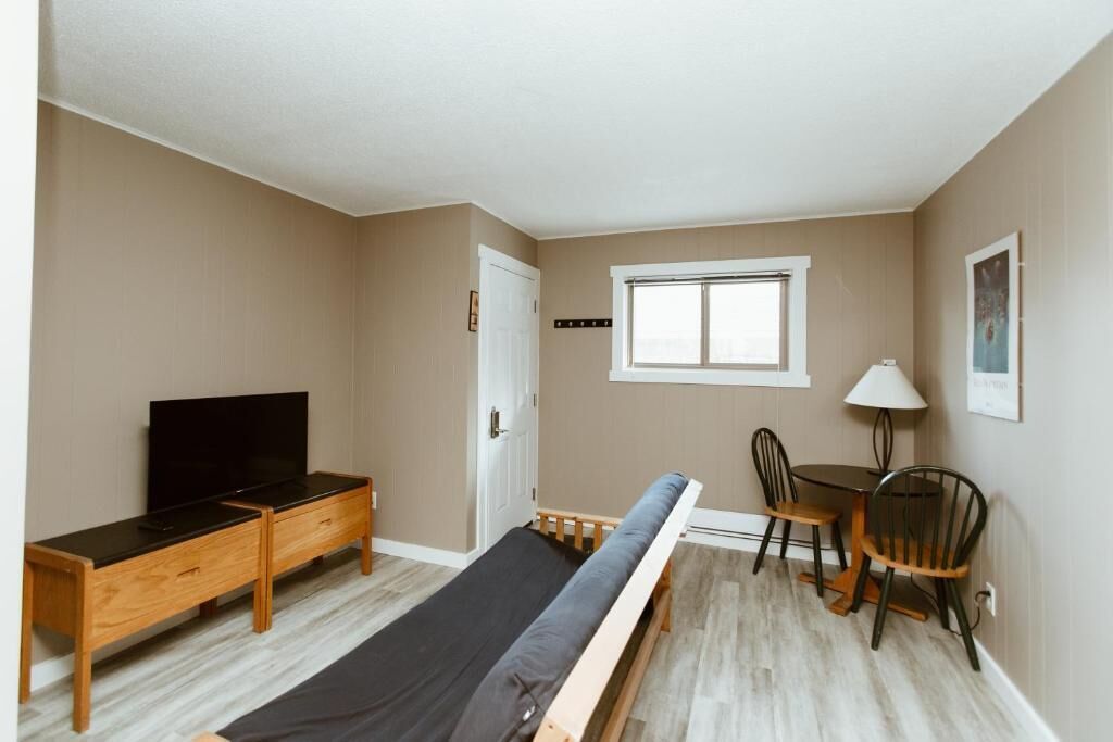 A bedroom with a bed, a TV, a desk, and a chair.