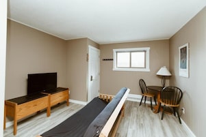 A bedroom with a bed, a TV, a desk, and a chair.