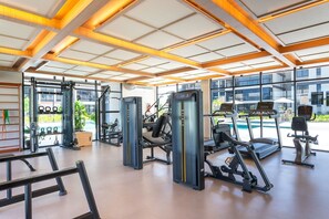 Una gimnàs moderna amb diversos equips d'exercici, grans finestres i vista exterior.