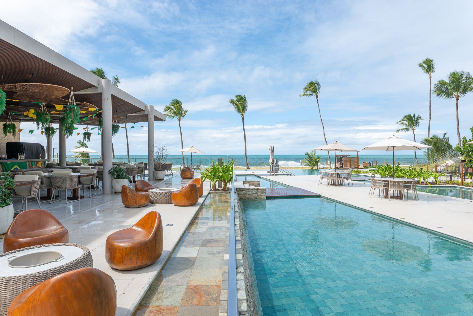 A poolside area with lounge chairs, a bar, and a view of the ocean.