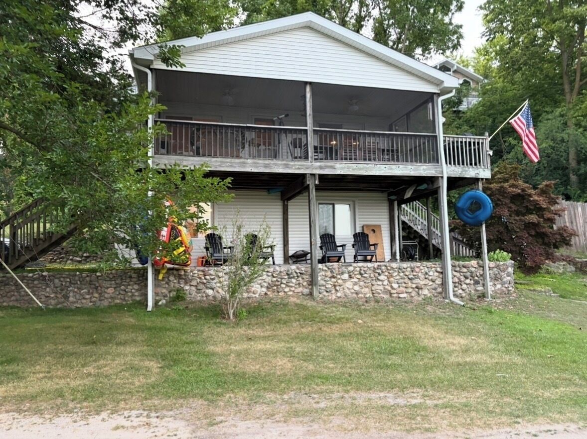 Una casa de dues plantes amb un balcó, una bandera i una paret de pedra.