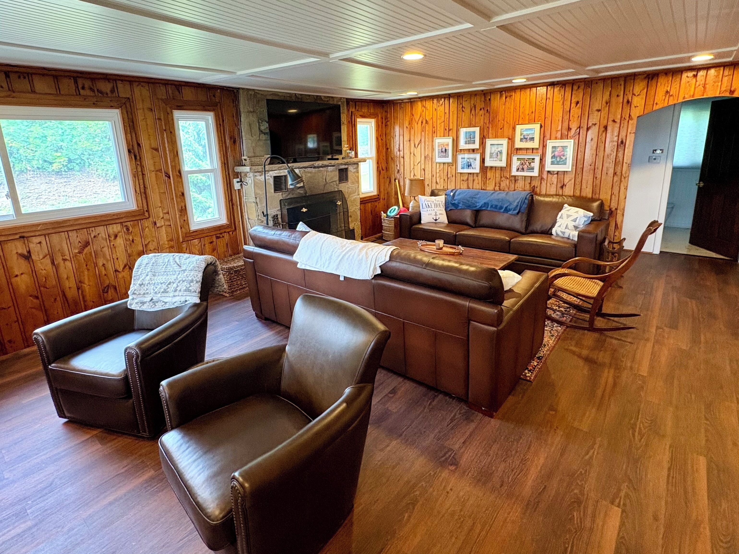 A cozy living room with leather furniture, a fireplace, and wooden paneling.