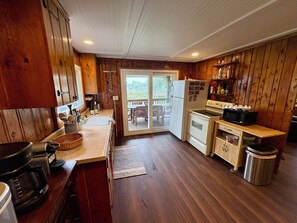 A kitchen with wooden cabinets, a refrigerator, a stove, and a microwave. - Lakefront home combining old school warmth and charm with clean, modern updates! (Onsted)