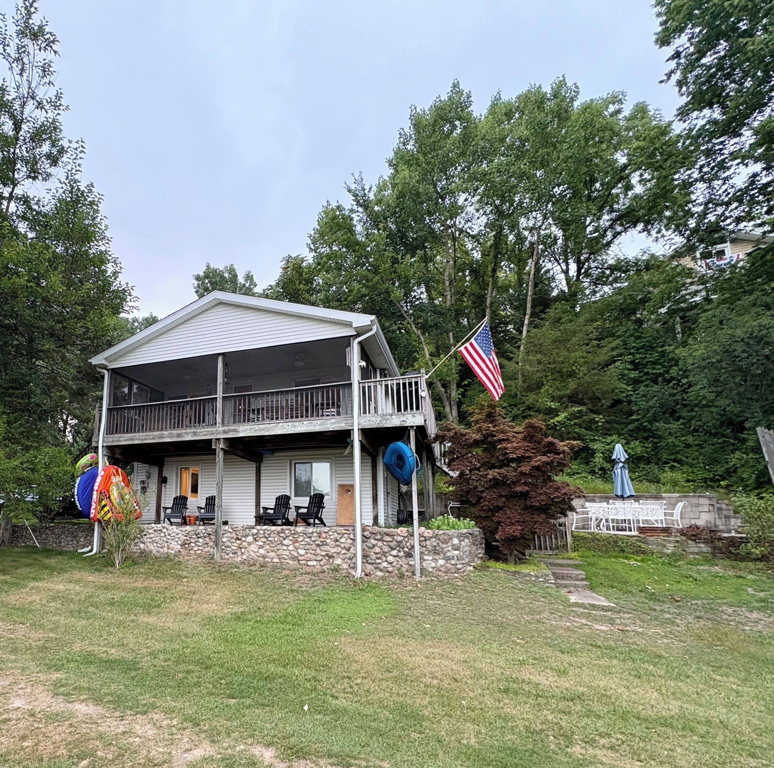A two-story house with a balcony, a flag, and outdoor seating.