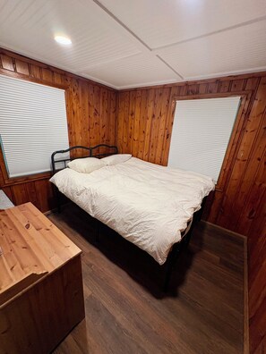 Ein Zimmer mit einem Bett, Holzwänden und einem Fenster.