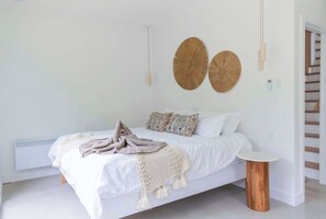 A bedroom with a bed, a bedside table, a wall-mounted lamp, and a round wall decoration.