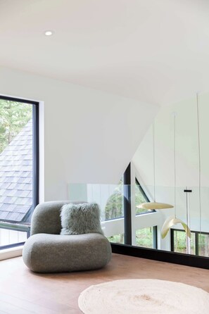 A modern interior with a large window, a plush armchair, and a minimalist design.