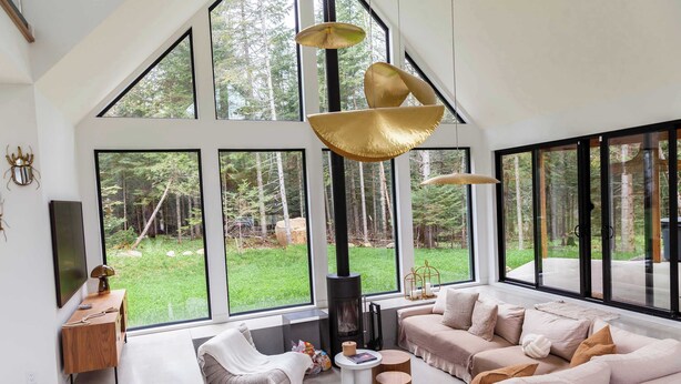 Ein geräumiges Wohnzimmer mit großem Fenster, Kamin und einer modernen Couch.