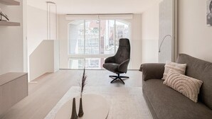 A modern living room with a sofa, a chair, and a coffee table. - Spacious Duplex in Knokke Centre (Knokke-Heist)