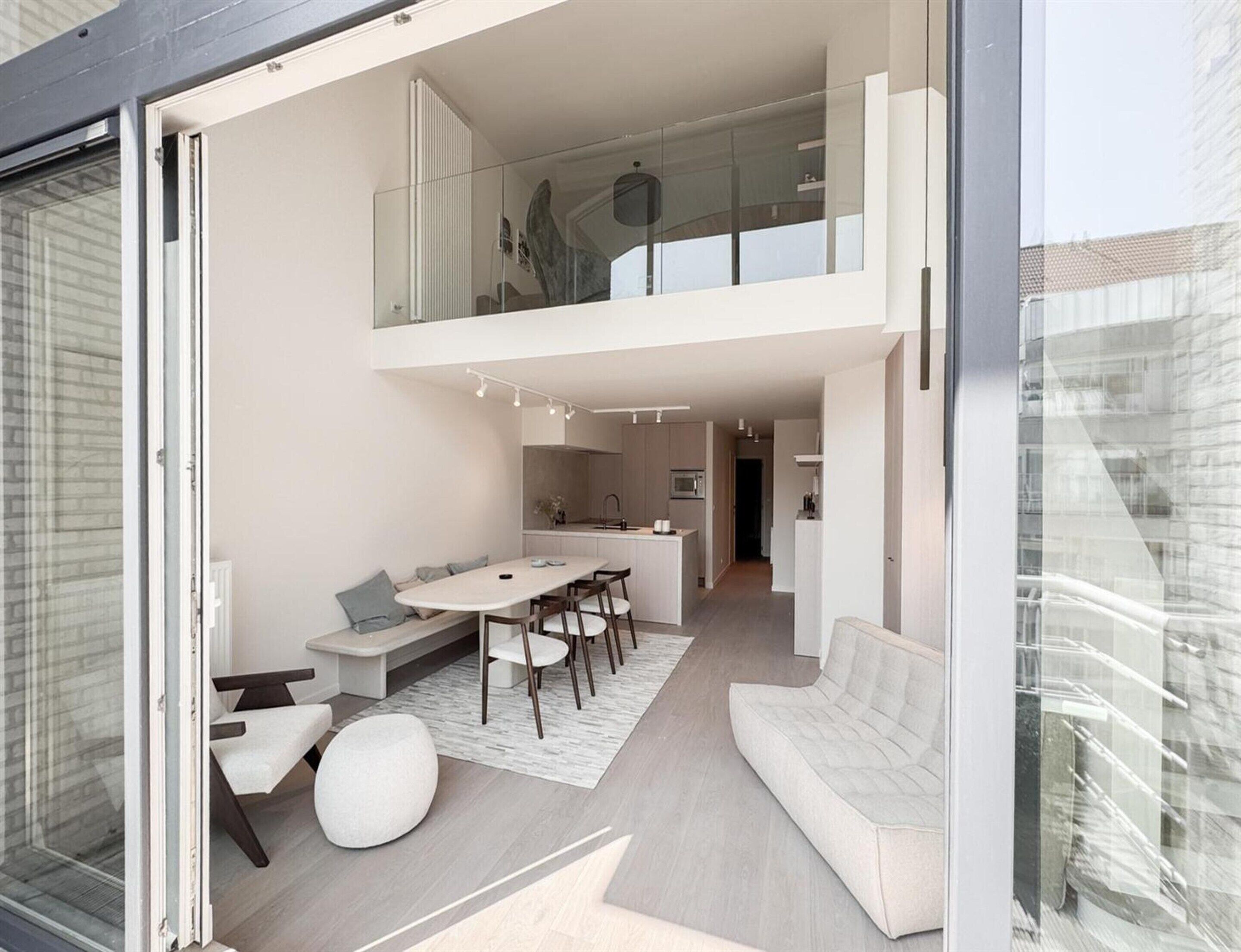 A modern interior with a dining area, sofa, and a kitchen.