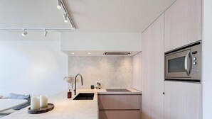 A modern kitchen with a built-in microwave, a sink, and a countertop. - Spacious Duplex in Knokke Centre (Knokke-Heist)
