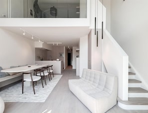 A modern interior with a dining area, a sofa, and a staircase. - Spacious Duplex in Knokke Centre (Knokke-Heist)