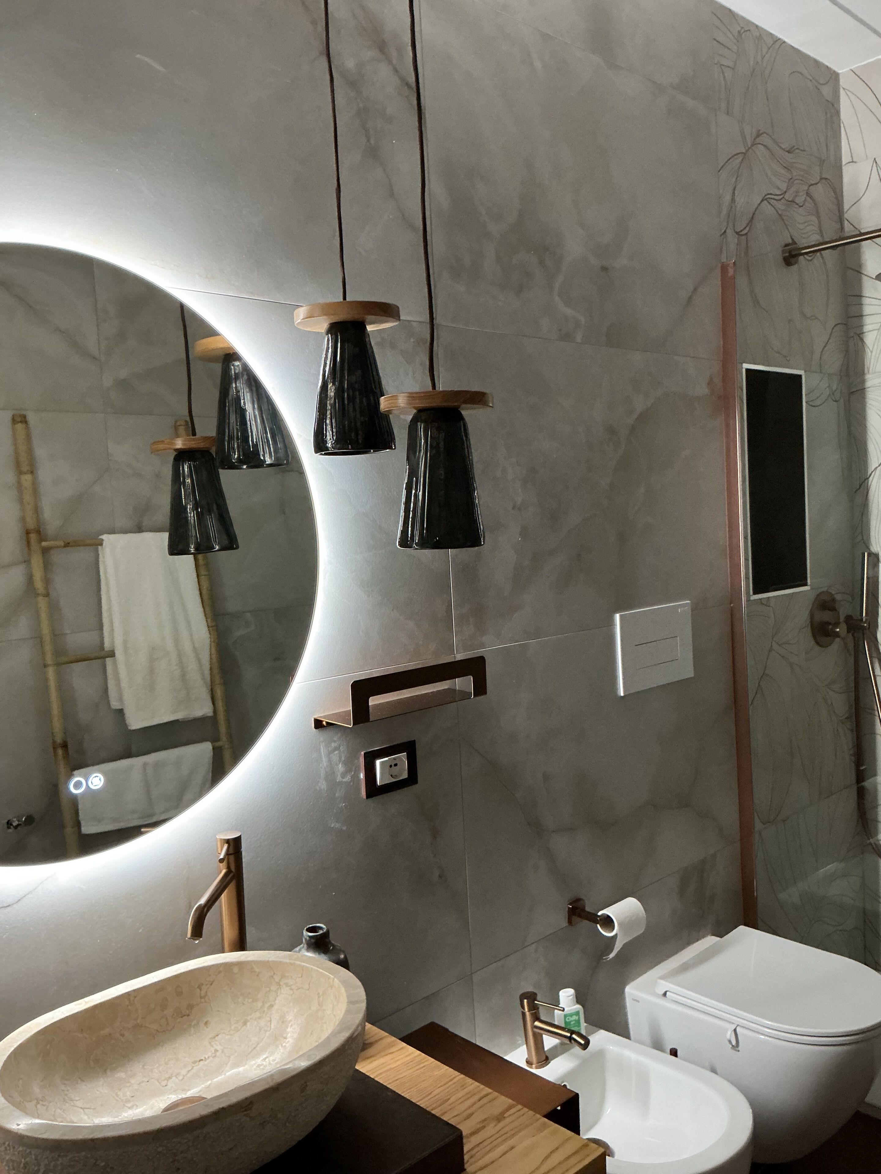 Un bany modern amb un mirall gran, un lavabo de pedra, un vàter i una zona de dutxa.