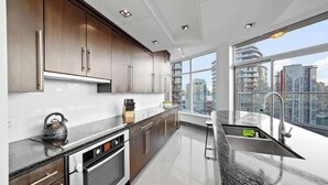 Una cocina moderna con electrodomésticos de acero inoxidable, armarios de madera y un amplio ventanal con vista a la ciudad.