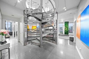 Ein modernes Interieur mit einer zentralen Wendeltreppe, einem großen Fenster mit Stadtblick und minimalistischer Gestaltung.