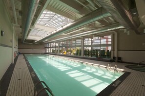 Ein Innenpool mit großen Glaswänden, einer Dachfensterdecke und sichtbaren Fenstern.