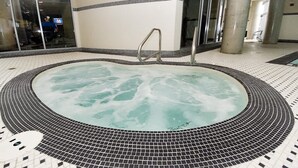 Un jacuzzi con suelo de baldosas y barandales de metal.