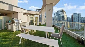 Terraza en la azotea con parrilla, asientos y vistas a la ciudad.