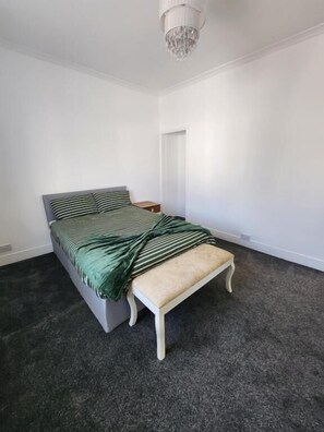 Ein Schlafzimmer mit Bett, einer Sitzbank, einer Tür und einer Chandelieber.
