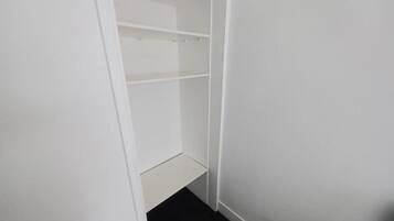 Un armario blanco con puertas abiertas, mostrando estantes y un espacio inferior.