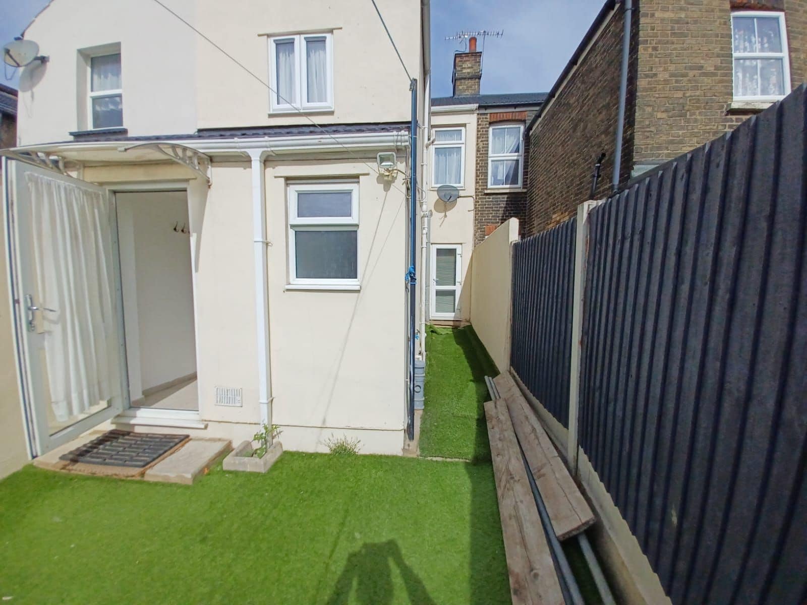 A residential property with a small garden, a garage, and a wooden fence.