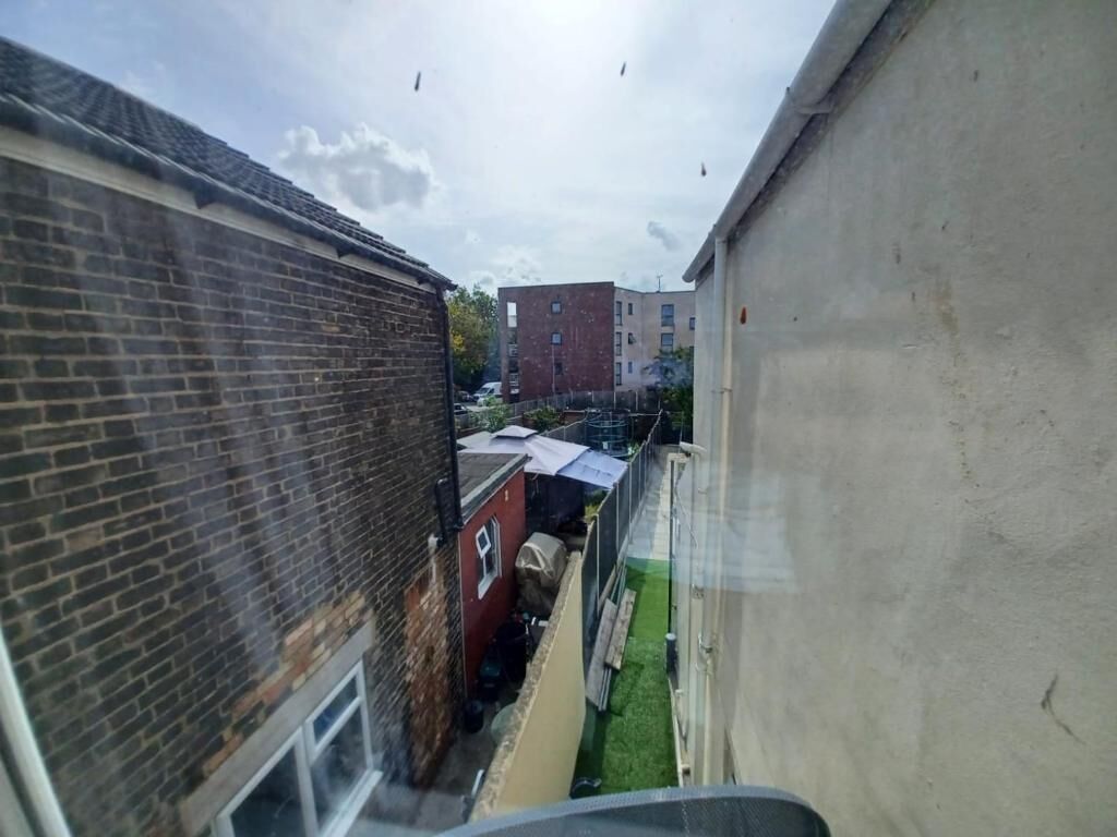 Un callejón estrecho con edificios de ladrillo a un lado y un muro de hormigón al otro.