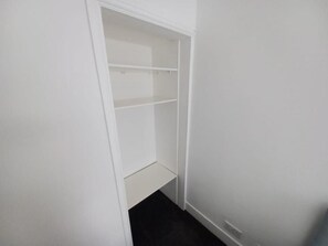 A white closet with multiple shelves and a lower compartment.