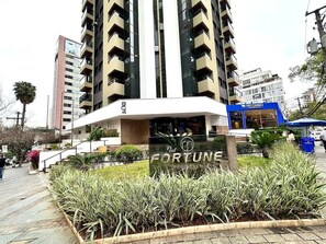 A modern building with a prominent entrance, a landscaped garden area, and a visible sign for PECORINO. - Fortune Residence (São Paulo)