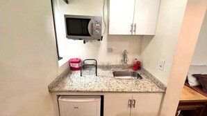 Cocina compacta con microondas, fregadero y un refrigerador pequeño.