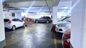 Garagem subterrânea de estacionamento com vários carros estacionados em vagas designadas.