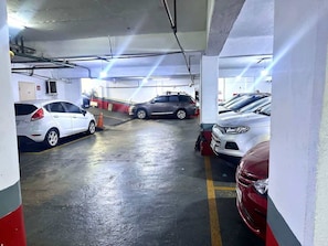 Garagem subterrânea de estacionamento com vários carros estacionados em vagas designadas.