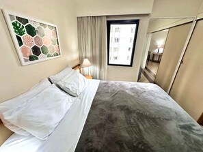 Ein Hotelzimmer mit Bett, Fenster, Lampe und Spiegel.