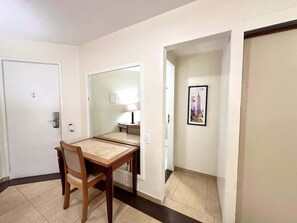 A hotel room with a dining table, chairs, a lamp, a framed picture on the wall, and a door with a lock. - Fortune Residence (São Paulo)