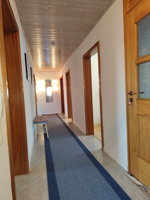 Ein Flur mit Holztüren, einem blauen Teppich und gerahmten Bildern an der Wand.