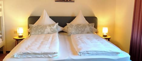 A double bed with two nightstands, each with a lamp, in a room with a painting on the wall.