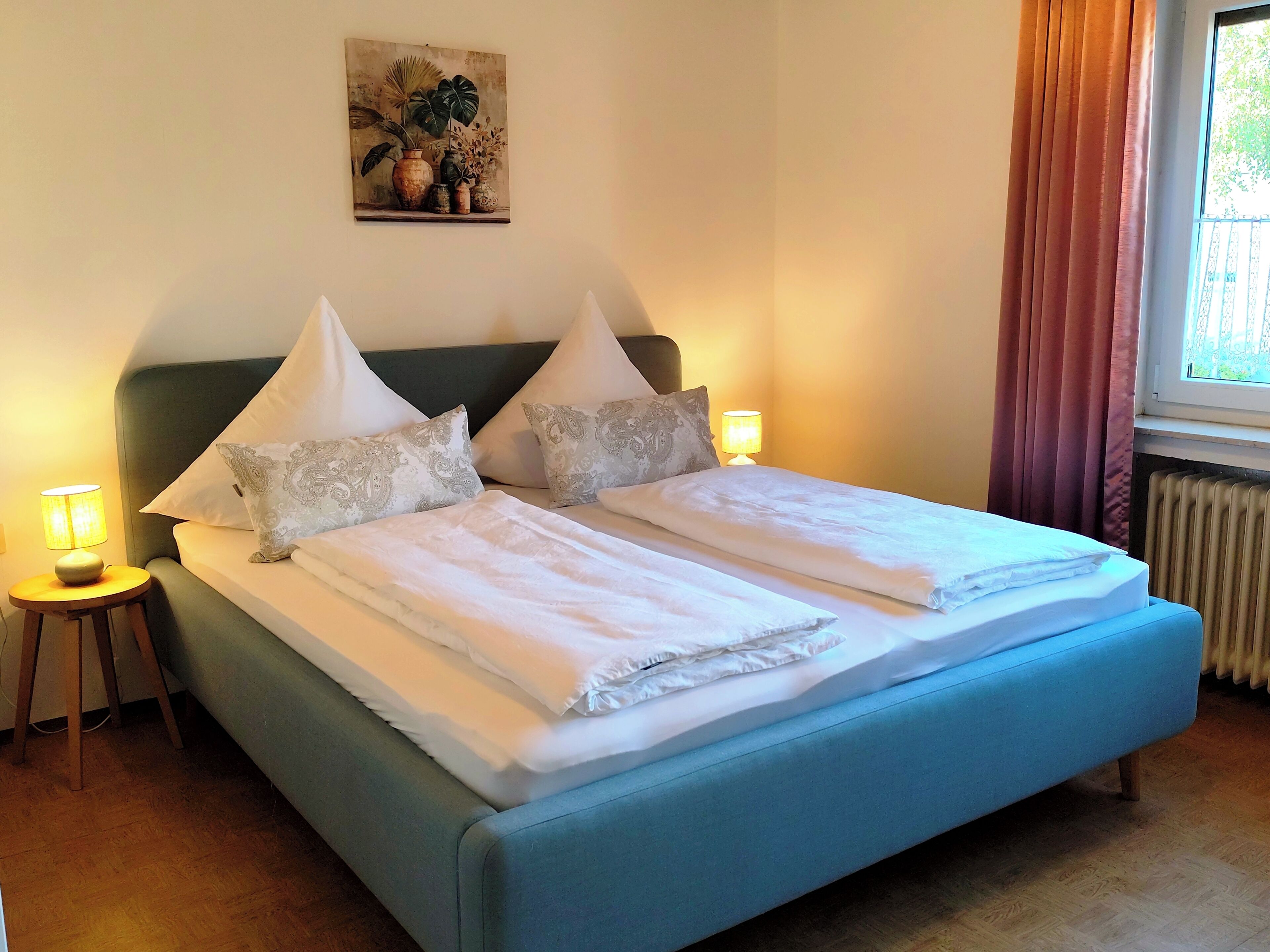 Una cama con dos almohadas, una lámpara de noche y un cuadro en la pared.