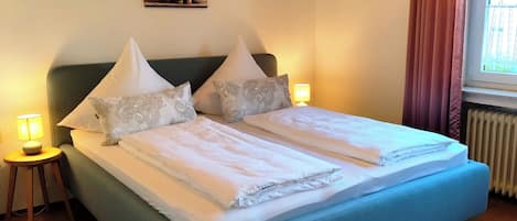 A bed with two pillows, a bedside lamp, and a painting on the wall.
