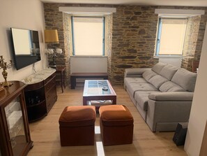 Ein Wohnzimmer mit Steinwand, einer Couch, einem Couchtisch und einem Fernseher.