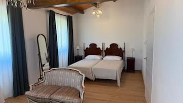 Quarto com duas camas, uma cadeira, um espelho e um lustre.