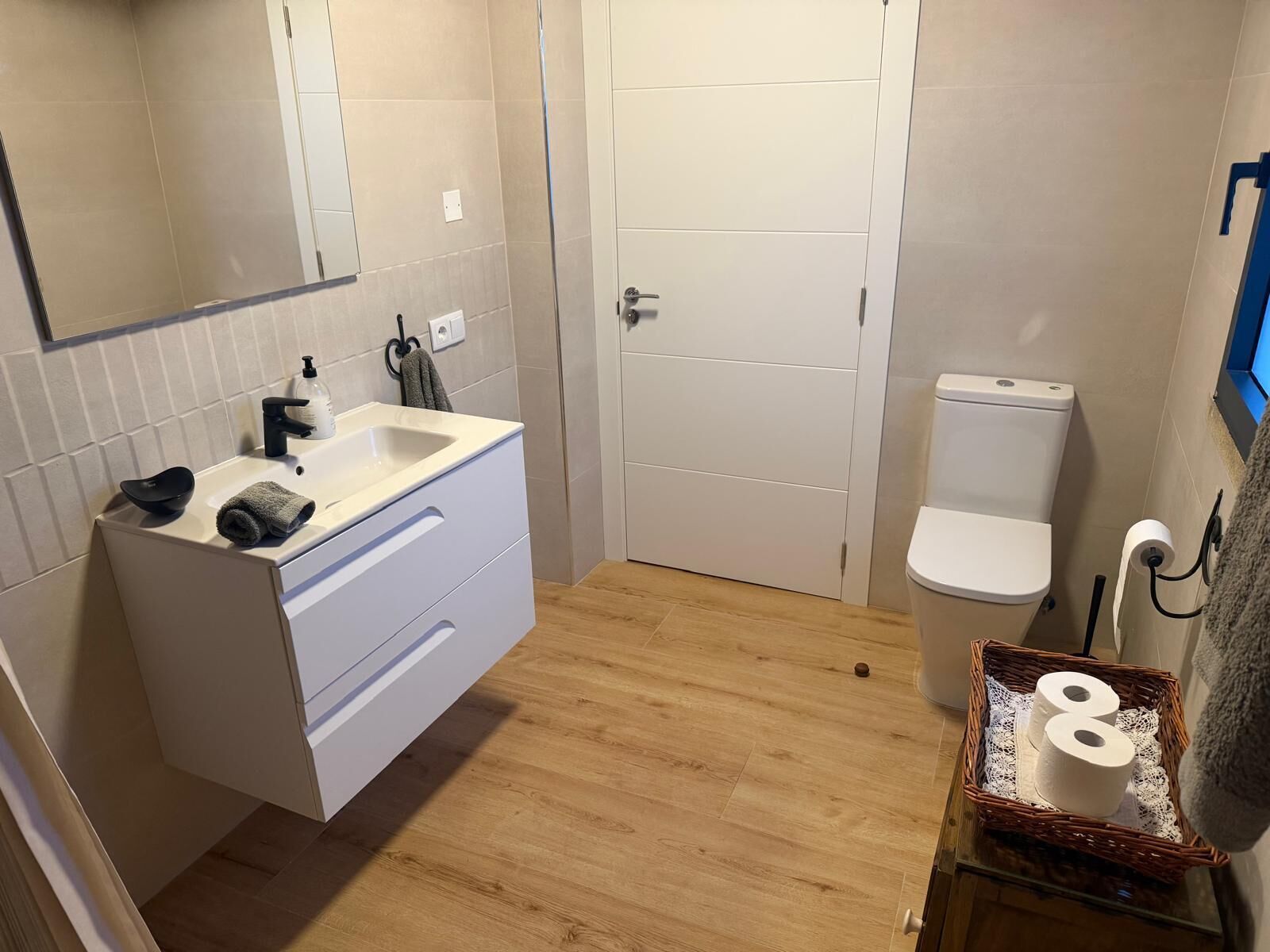Kylpyhuone, jossa on valkoinen pesuallas, wc-istuin ja peili.