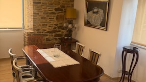 Ein Essbereich mit einem Holztisch, Stühlen, einer Steinwand, einer Lampe und einem gerahmten Bild.